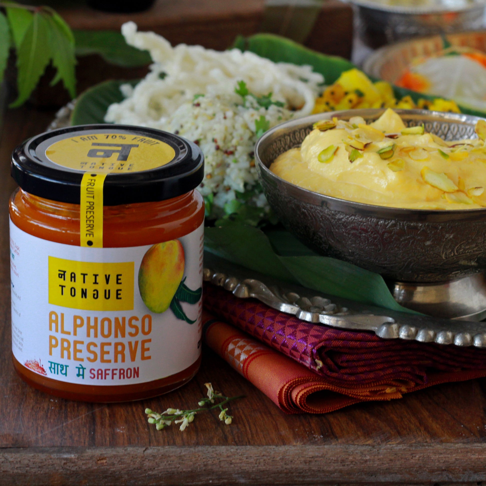 Jar of Alphonso Preserve with a bowl of Mango shrikhand on a wooden table