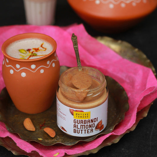 Jar of Gurmandi Almond Butter with a cup of creamy beverage on a decorative tray.