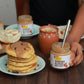 Stack of pancakes with almond butter on a wooden table, featuring a jar of almond butter.