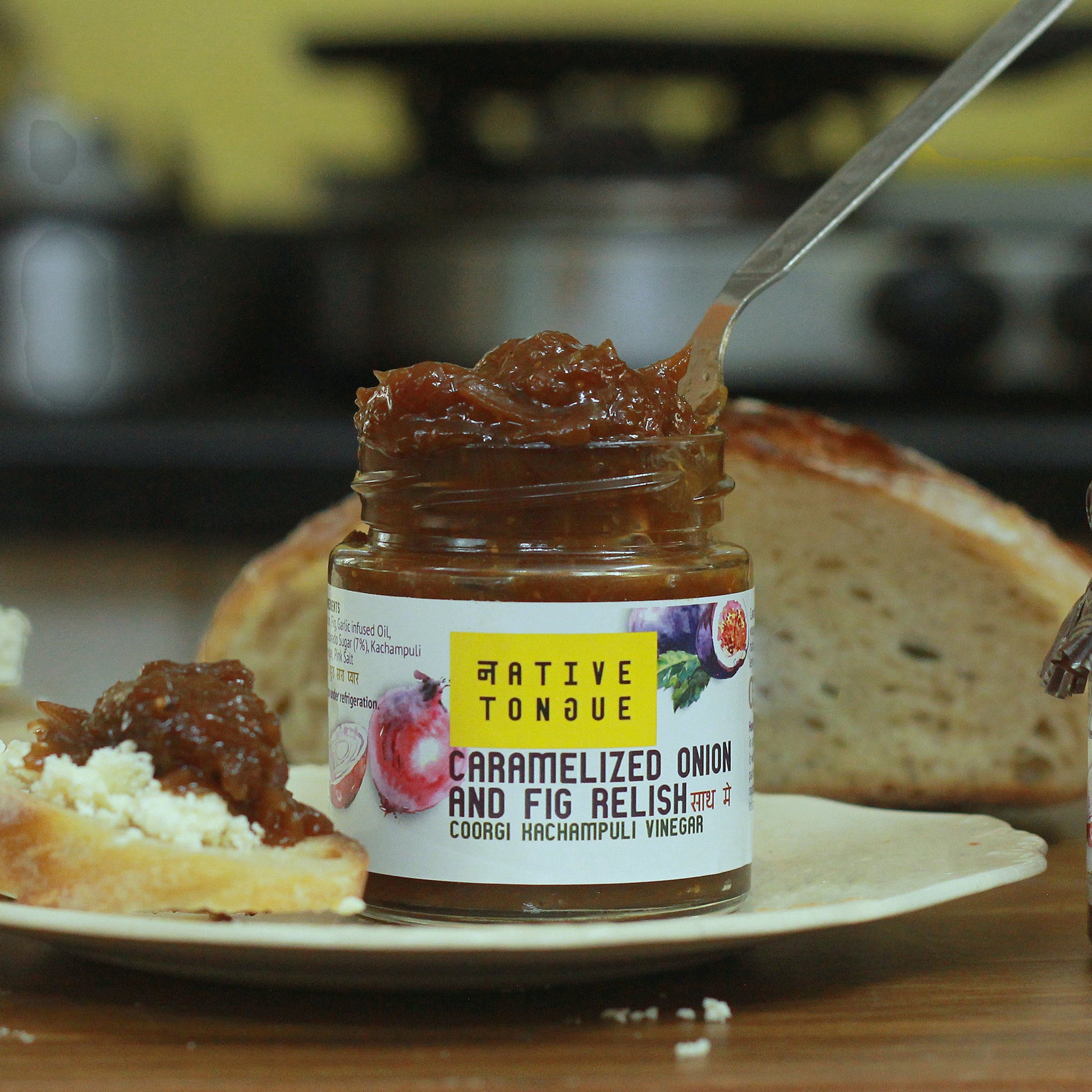 Two jars of relish on a wooden table with bread slices.